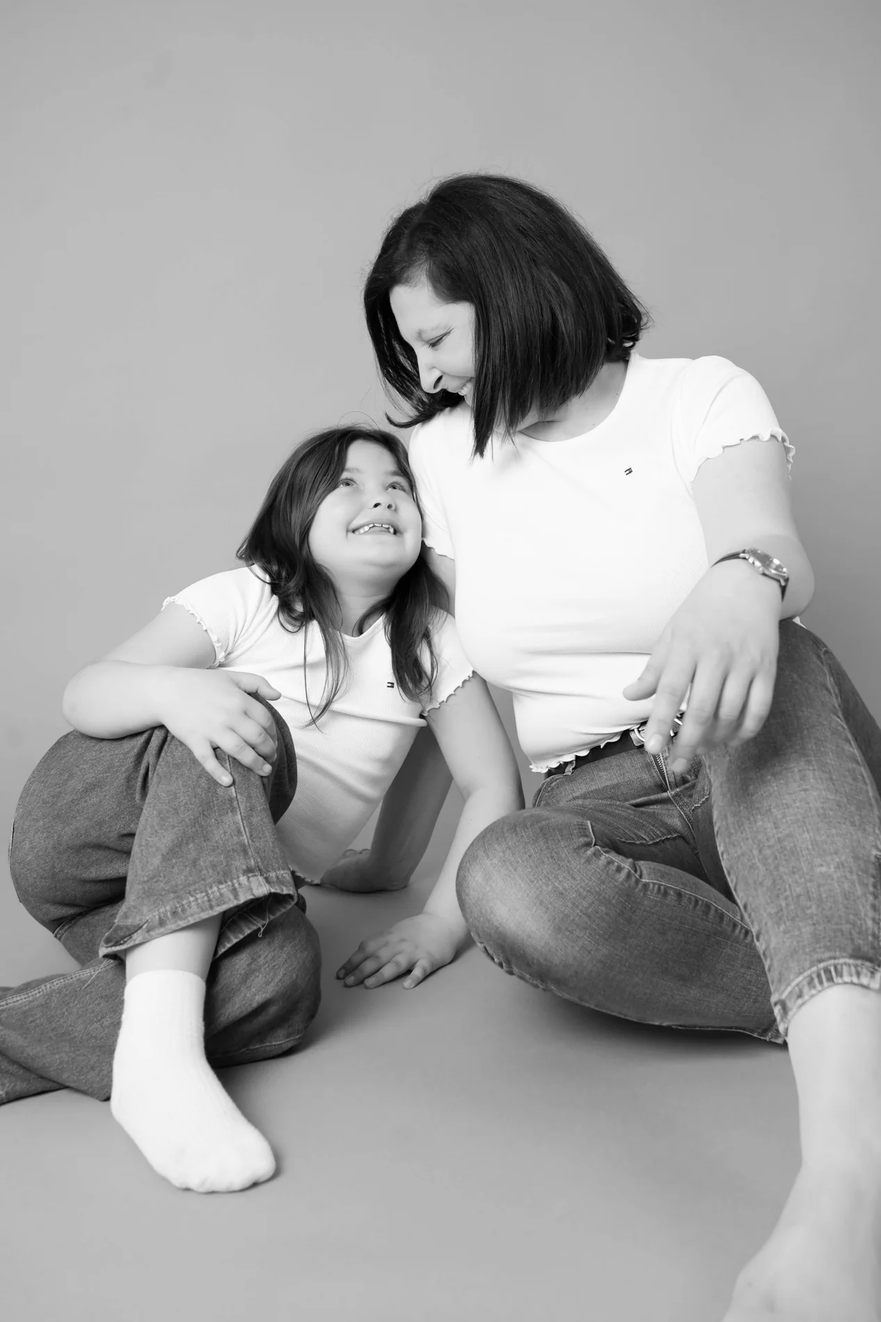 Schwarz-Weiß-Bild von Frau und Mädchen, die am Boden sitzen und einander anlächeln
