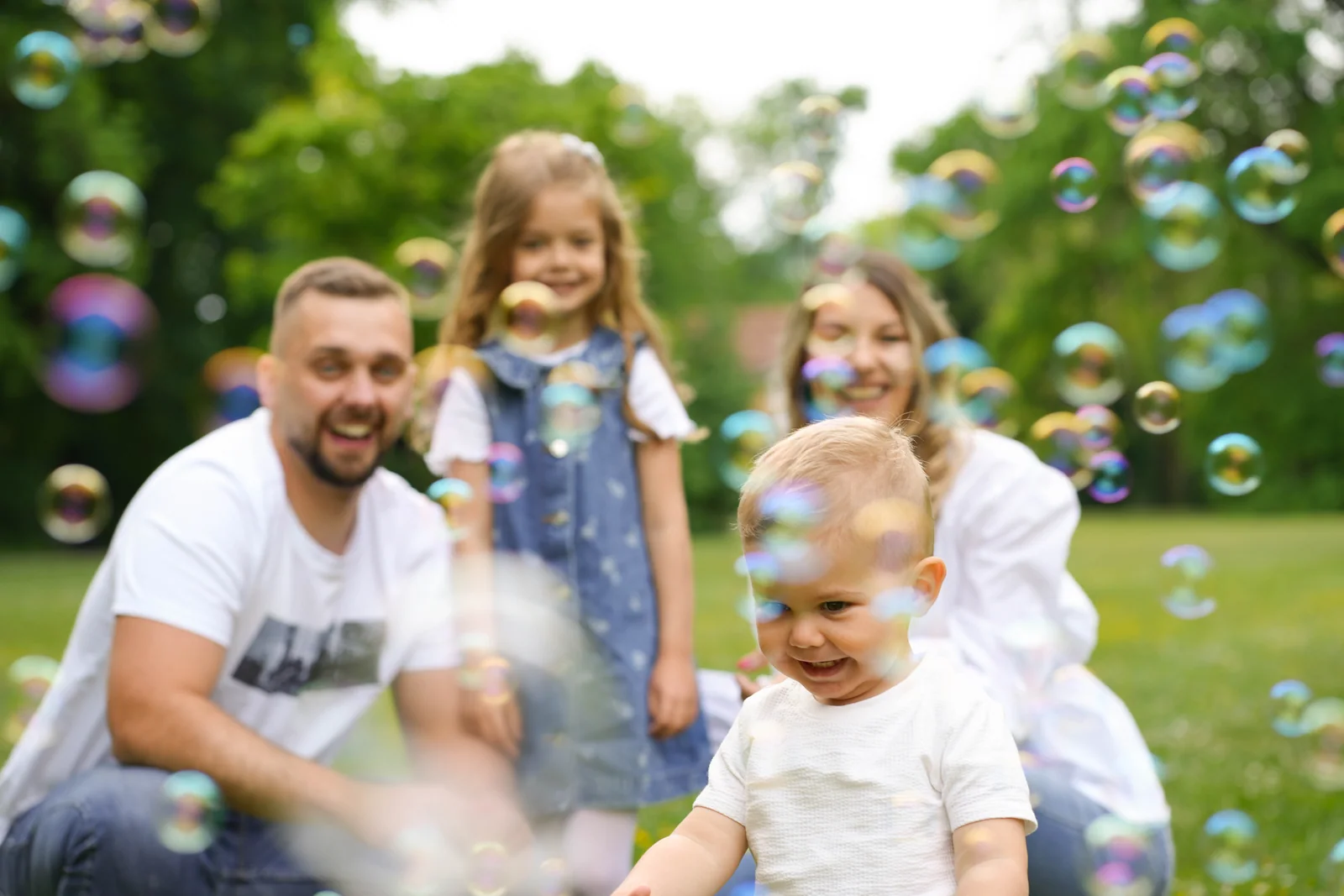 Familienfoto im Grünen: Ein kleiner Junge zwischen Seifenblasen vor drei weiteren Personen
