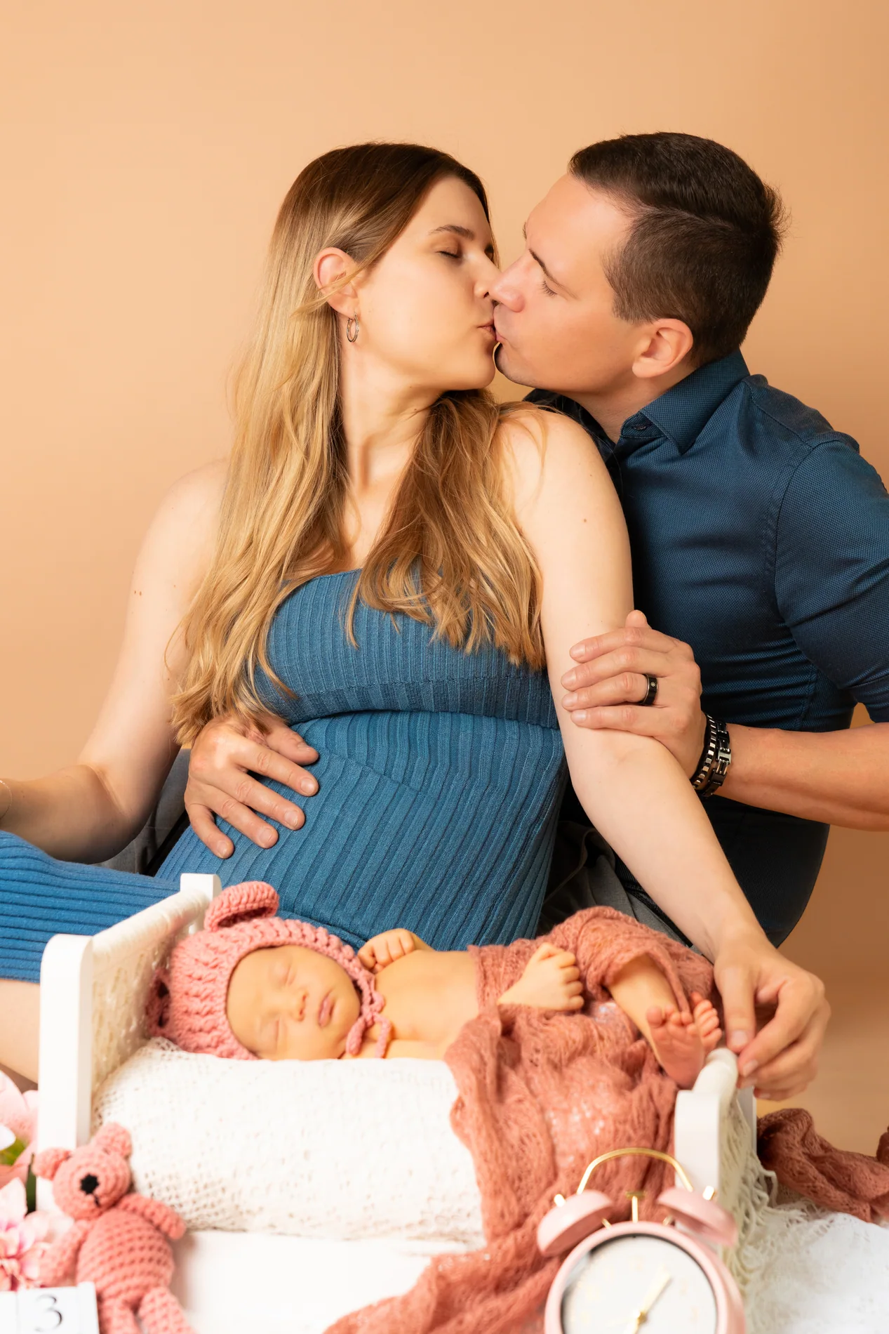 Ein Paar küsst sich hinter einem schlafenden Baby in einem rosa ausgelegten Körbchen