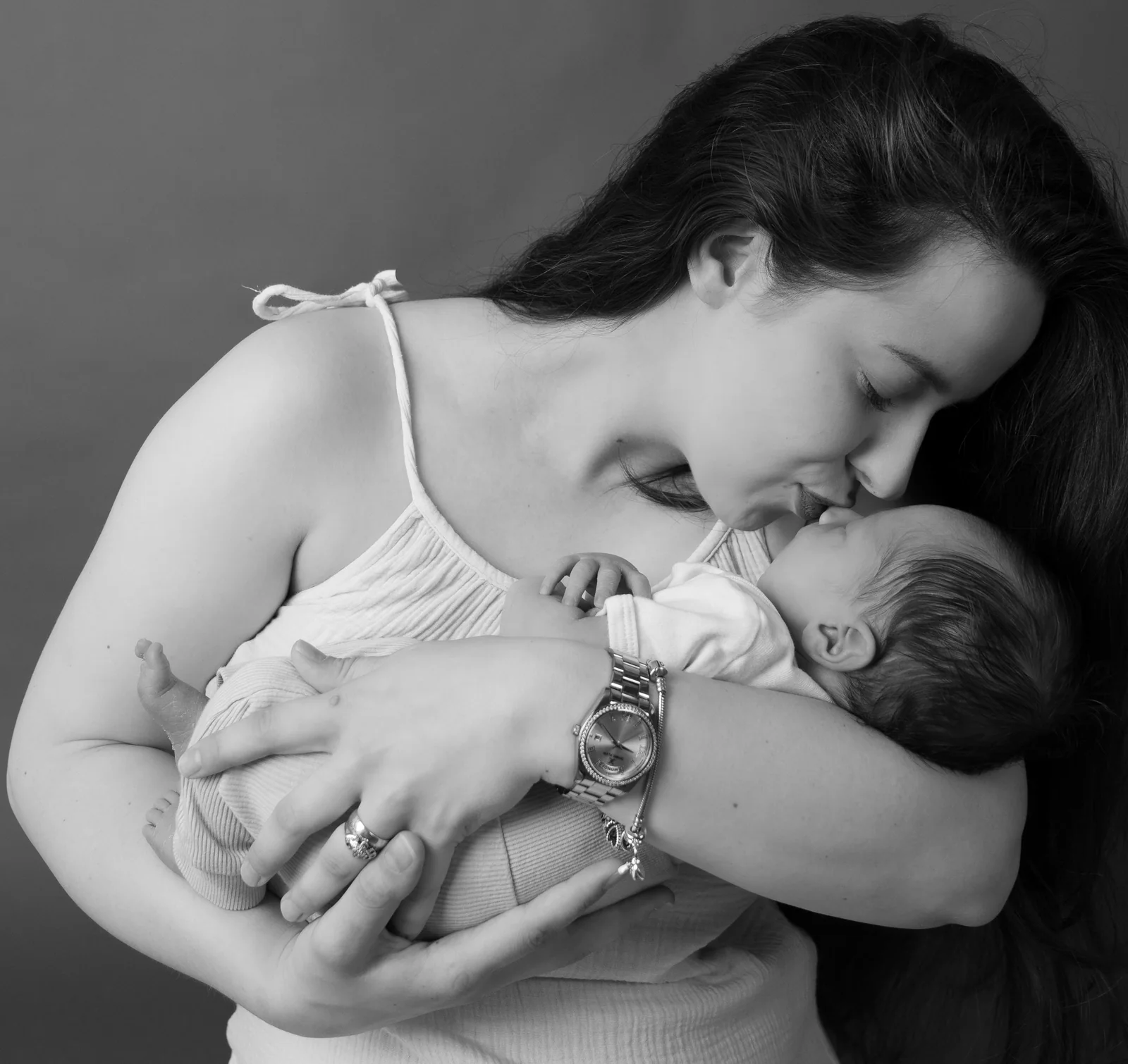 Schwarzweißfoto einer Frau, die ihr Gesicht zu einem Baby in der Armbeuge neigt und es küsst